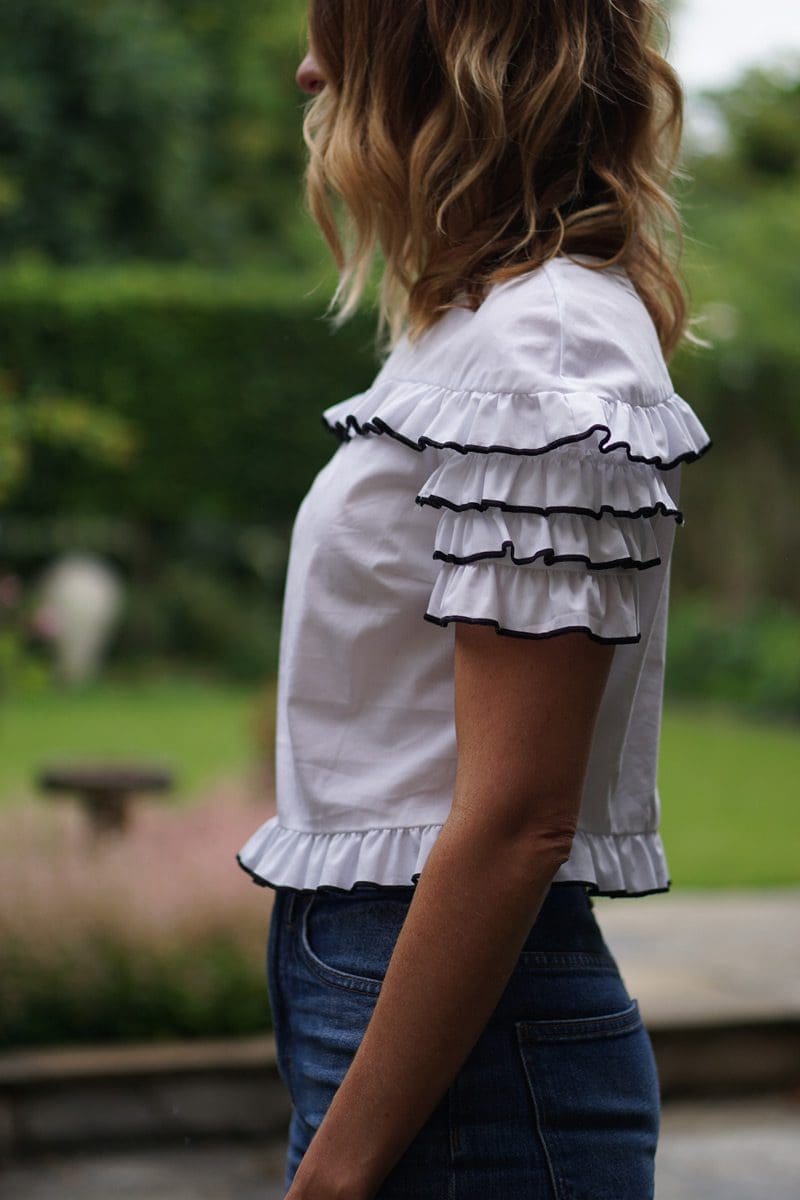 An image of a pear shaped women wearing a top with ruffles to balance her body shape