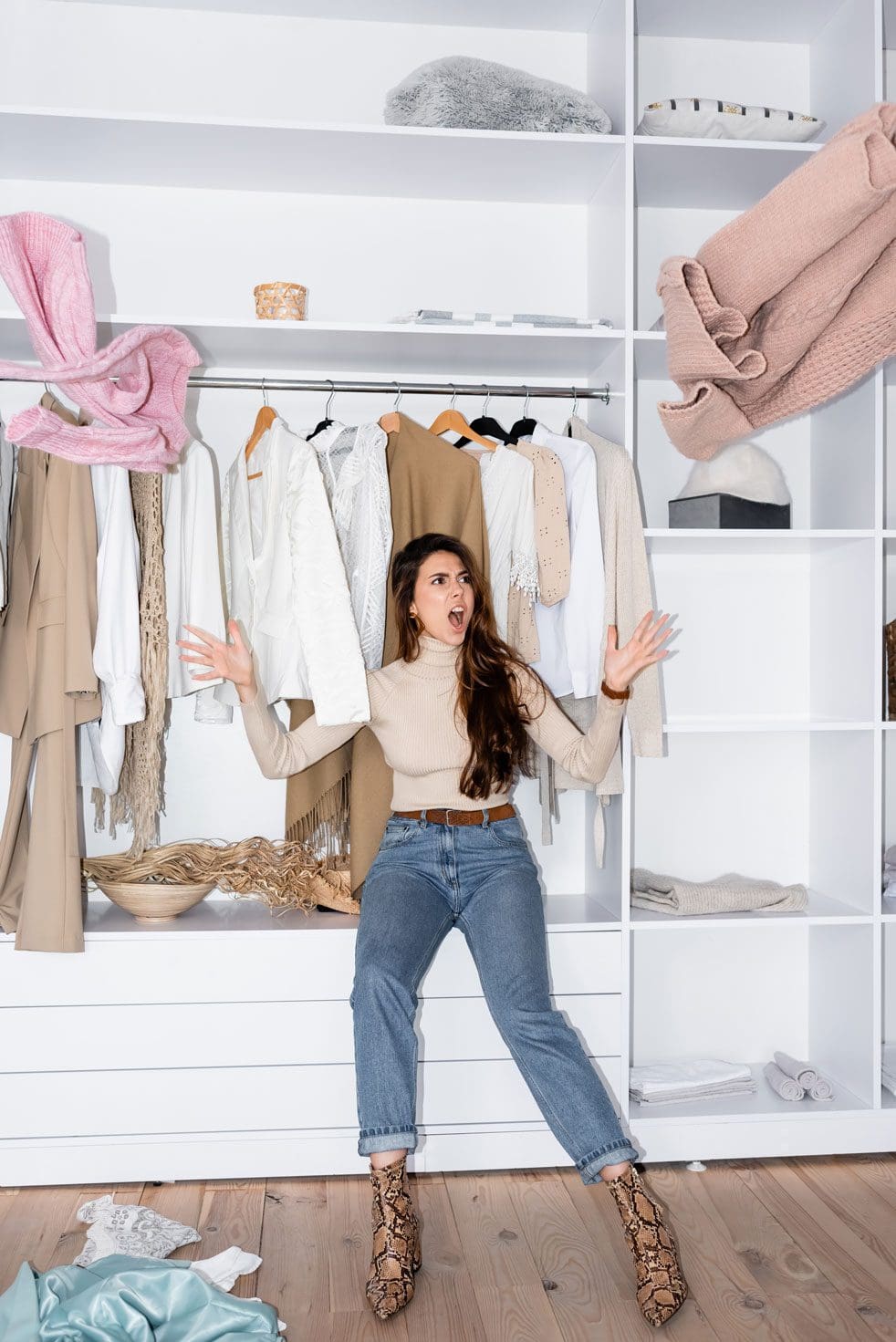 An image of an angry women sat in a wardrobe throwing her clothes out